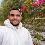 Grower in a high-tech tomato greenhouse with LED grow lights, where limiting ventilation helps manage heat stress and crop VPD
